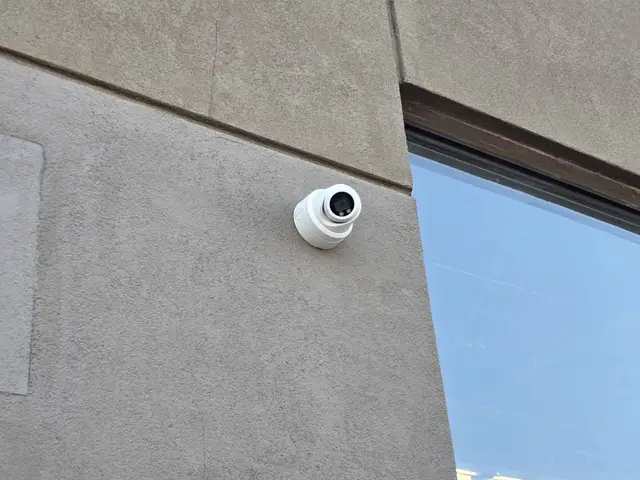 Turret camera on a commercial wall beside a window