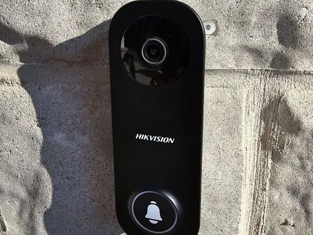 Black video doorbell installed on a stucco wall